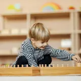 Ein Junge spielt konzentriert mit Holzbausteinen in einem Montessori Kindergarten.