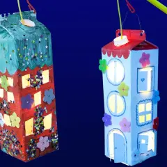 Zwei selbstgebastelte Laternen in Hausform, leuchten im Dunkeln. Kinder haben hier ihre Kreativität beim Laternen basteln gezeigt.
