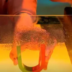 Hände halten Hufeisenmagnet, der Eisenpulver für Magnetismus-Experimente anzieht.