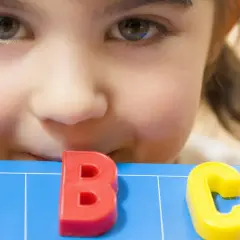 Ein neugieriges Kind lernt spielerisch das ABC. Perfekt für lustige Spiele zum Schulanfang!