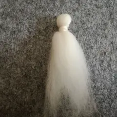 Ein weißer Wattebausch, der wie ein Kopf und ein Kleid aussieht, liegt auf grauem Filz. Dies ist der Anfang vom engel filzen.