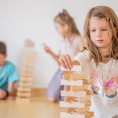 Kinder bauen in der Bauecke im Kindergarten einen hohen Turm aus Holzklötzen.