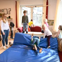 Kinder genießen spielzeugfreie Zeit in der Kita, klettern und toben auf einer blauen Matte.