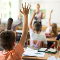 Erste Klasse: Kinder melden sich eifrig, um Fragen zu beantworten. Hier lernt man das ABC und die ersten Zahlen.