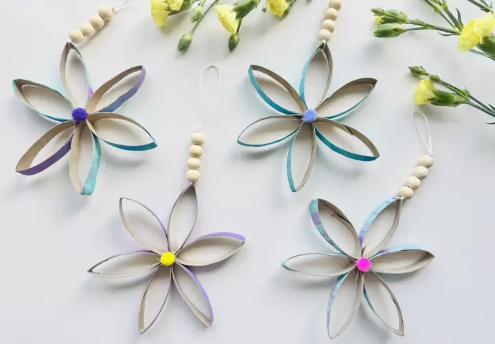 Blumen aus Klopapierrollen: basteln mit Klopapierrollen einfach. Bunte Blüten mit Holzperlen und Pompons, daneben gelbe Blumen.