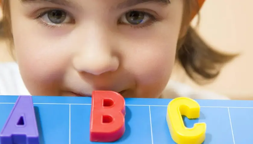 Ein neugieriges Kind lernt spielerisch das ABC. Perfekt für lustige Spiele zum Schulanfang!