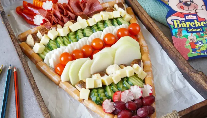Ein kreatives Buffet für die Einschulung: Würstchen, Käse, Gemüse und Obst in einem tollen Muster arrangiert. Perfekt für eine Gartenparty!