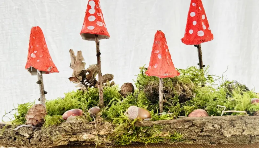 Kleine Waldgeister: Rote Fliegenpilze, gebastelt mit Kindern, stehen auf Moos und Ästen.