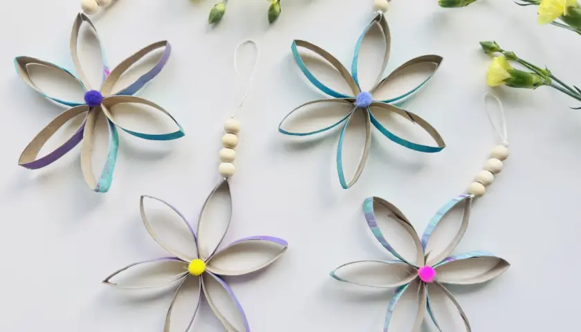 Blumen aus Klopapierrollen: basteln mit Klopapierrollen einfach. Bunte Blüten mit Holzperlen und Pompons, daneben gelbe Blumen.