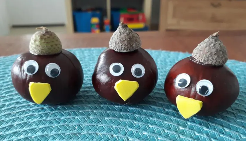 Drei lustige Kastanien-Figuren mit Eichelkappen und Wackelaugen, ein Beispiel für einfaches Kastanien basteln.