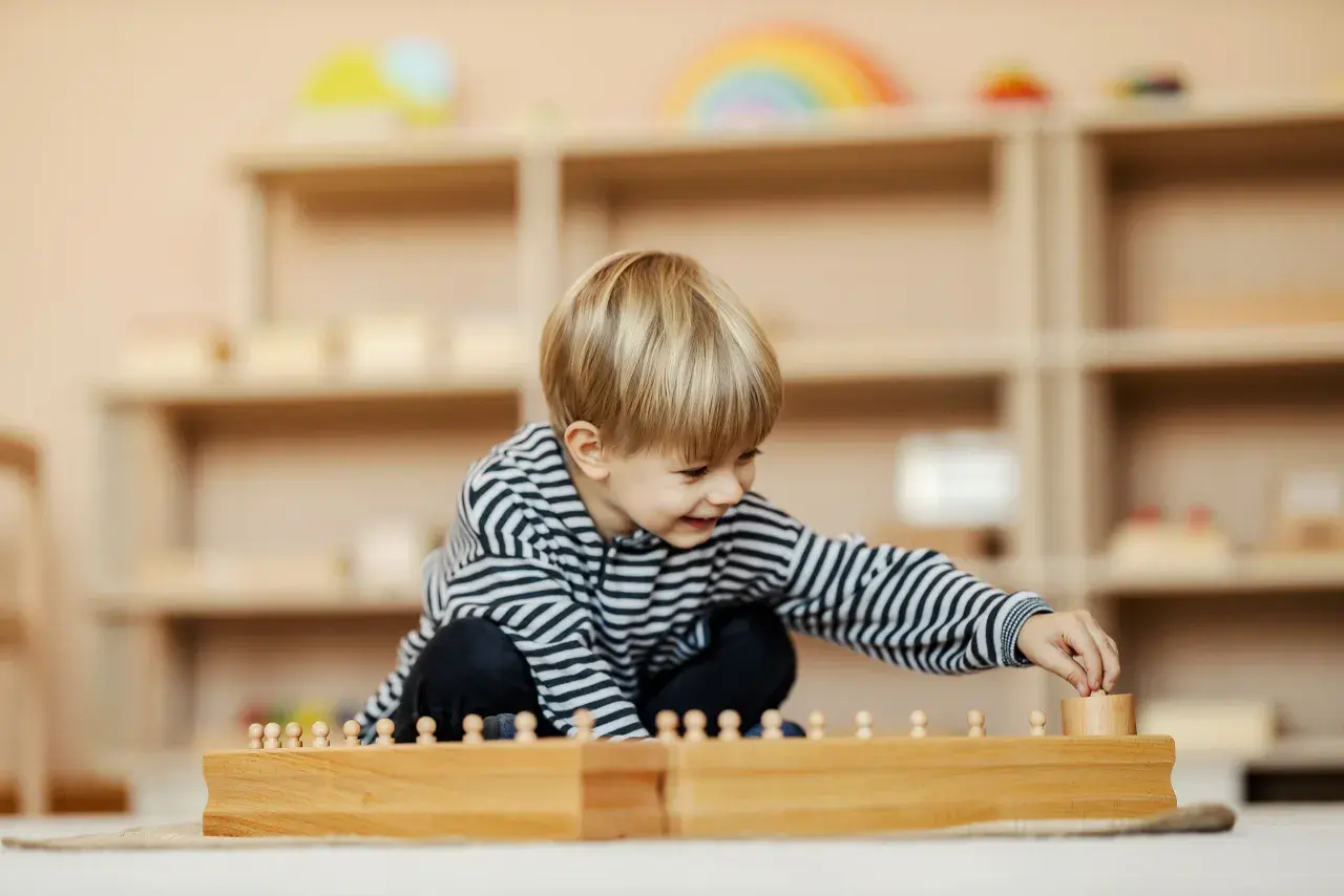 Ein Junge spielt konzentriert mit Holzbausteinen in einem Montessori Kindergarten.