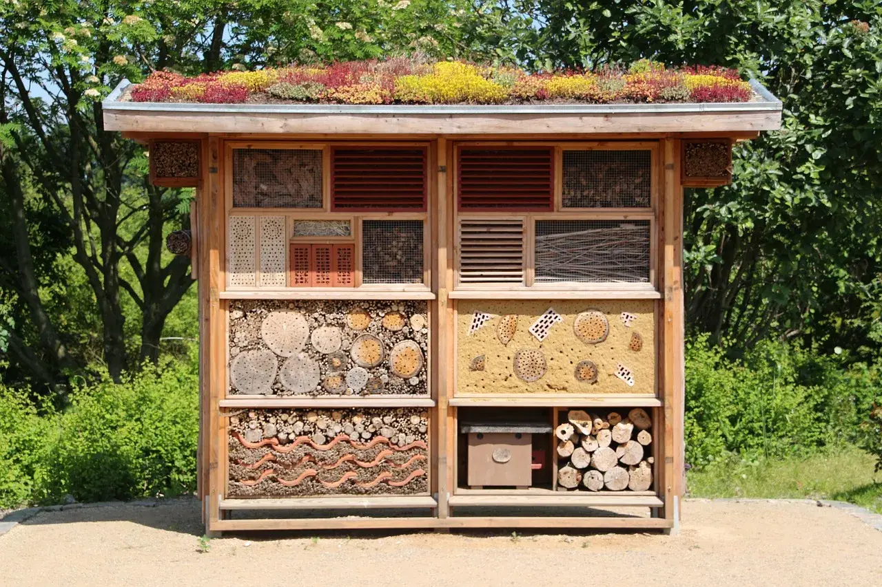 Ein großes Insektenhotel, das Kinder selber bauen können, mit vielen Fächern für verschiedene Insekten. Das Dach ist begrünt.