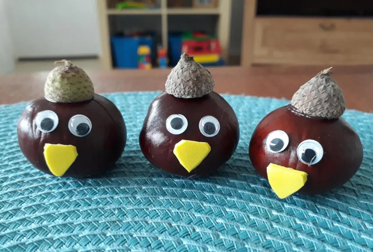 Drei lustige Kastanien-Figuren mit Eichelkappen und Wackelaugen, ein Beispiel für einfaches Kastanien basteln.