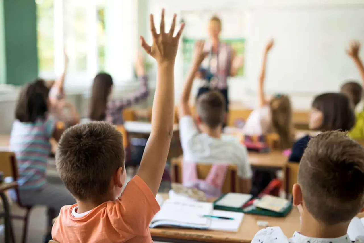 Erste Klasse: Kinder melden sich eifrig, um Fragen zu beantworten. Hier lernt man das ABC und die ersten Zahlen.