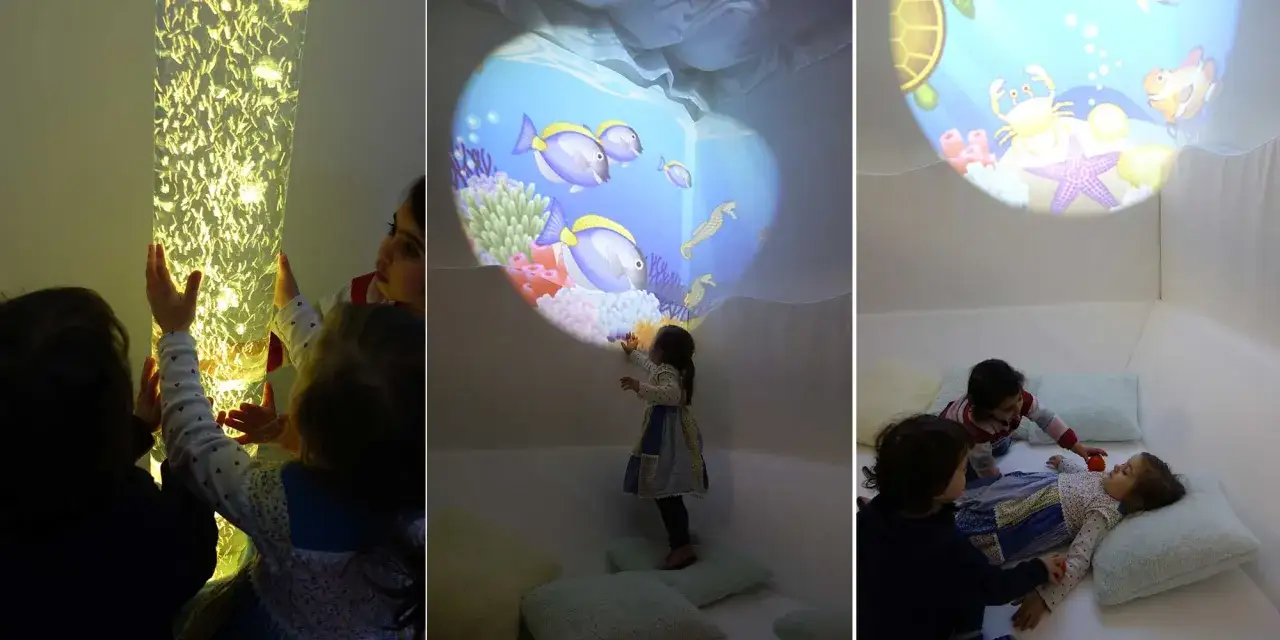 Kinder erkunden einen Snoezelraum Kita mit leuchtender S&auml;ule und Unterwasserprojektionen.