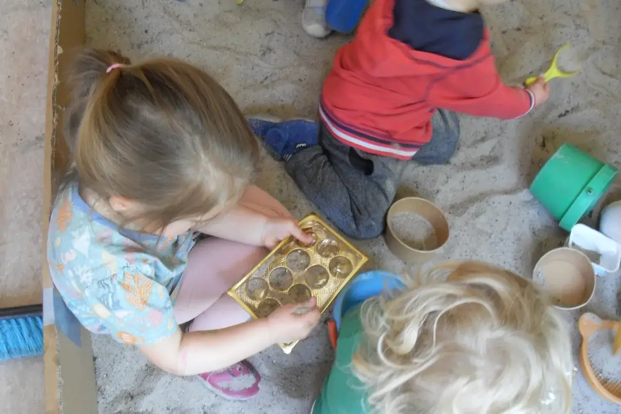 Kinder genießen spielzeugfreie Zeit in der Kita und bauen im Sandkasten.