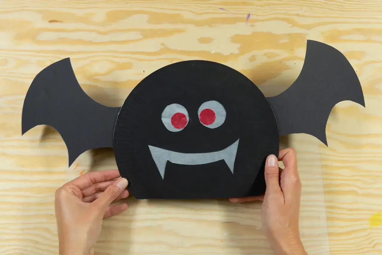 Fledermäuse für Halloween basteln Kita: Ein lustiger Fledermaus-Bastelvorschlag mit großen roten Augen und spitzen Zähnen.