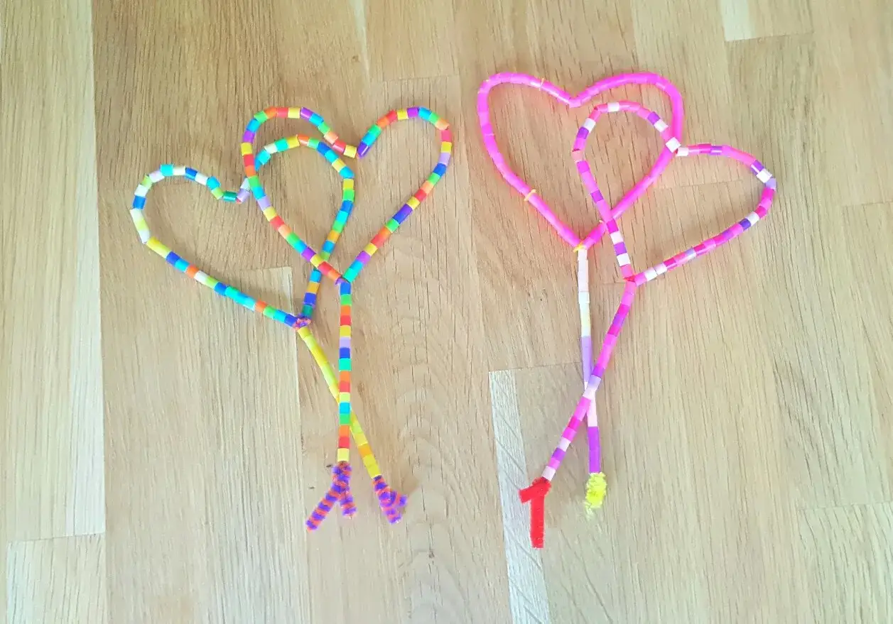Bunte Herzen aus Perlen, perfekt zum Muttertagsgeschenk basteln. Zwei Herzen, eines bunt, das andere in Rosa-Tönen, mit kleinen Anhängern.