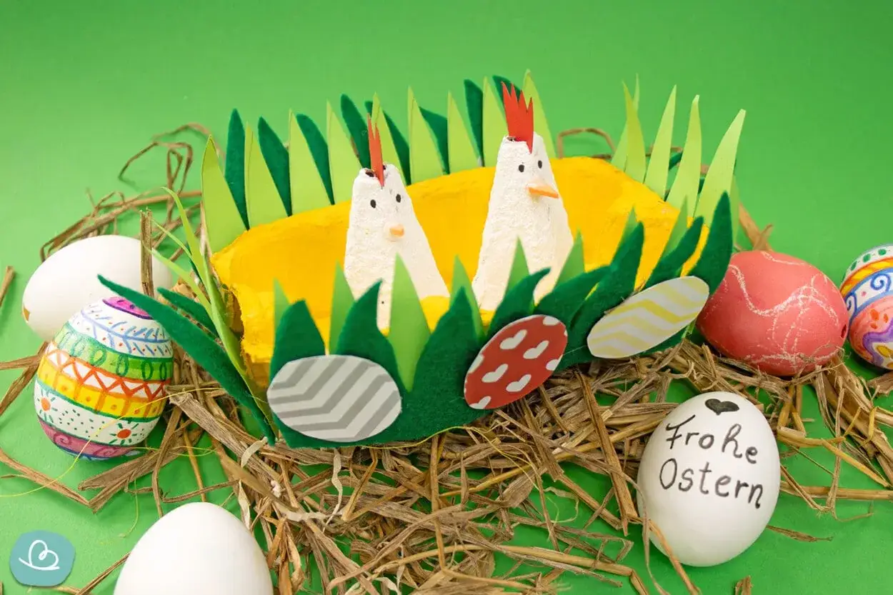 Zwei Küken aus Eierkartons in einem Nest mit bunten Ostereiern. Perfekt für kinder ostern basteln schnell.