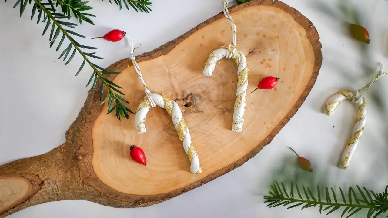 Selbstgemachte Weihnachtsdeko aus modelliermasse: Kinder basteln s&uuml;&szlig;e Zuckerstangen-Anh&auml;nger mit Glitzer.