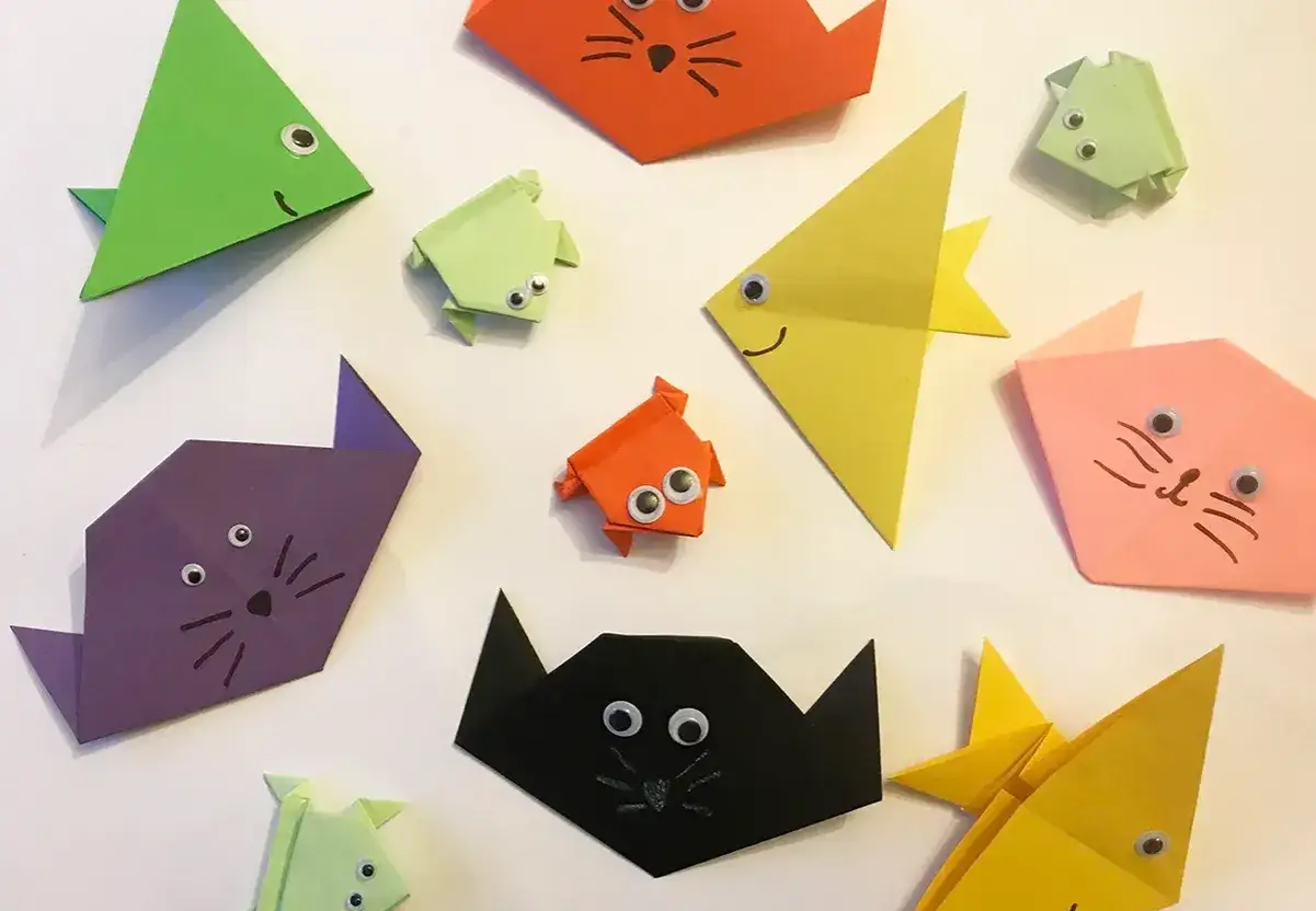 Bunte Origami-Tiere, wie Katzen und Fische, mit aufgemalten Gesichtern und Knopfaugen. Ein fr&ouml;hlicher Haufen Origami Kinder.