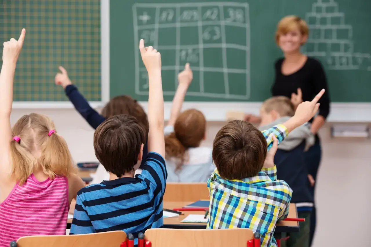 Schüler melden sich im Unterricht, um Fragen zu beantworten. Hier wird gezeigt, was man in der ersten Klasse lernt: Rechnen und Zuhören.