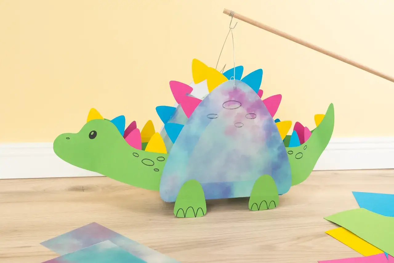 Ein gr&uuml;ner Dinosaurier-Laternen-Bastelprozess, mit bunten Zacken und einem marmorierten K&ouml;rper.
