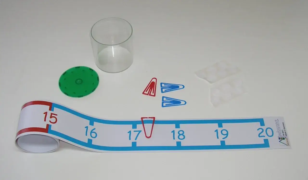 Zahlenstrahl bis 20 zum ausdrucken mit Zahlen von 15 bis 20, Büroklammern, Klebepunkten, einem grünen Spielstein und einem Glas.