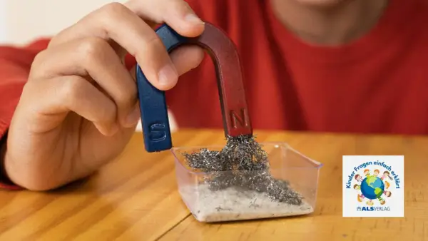 Ein Kind experimentiert mit einem Hufeisenmagneten und Metallspänen. Ein spannendes Thema für den Magnetismus in der Grundschule.